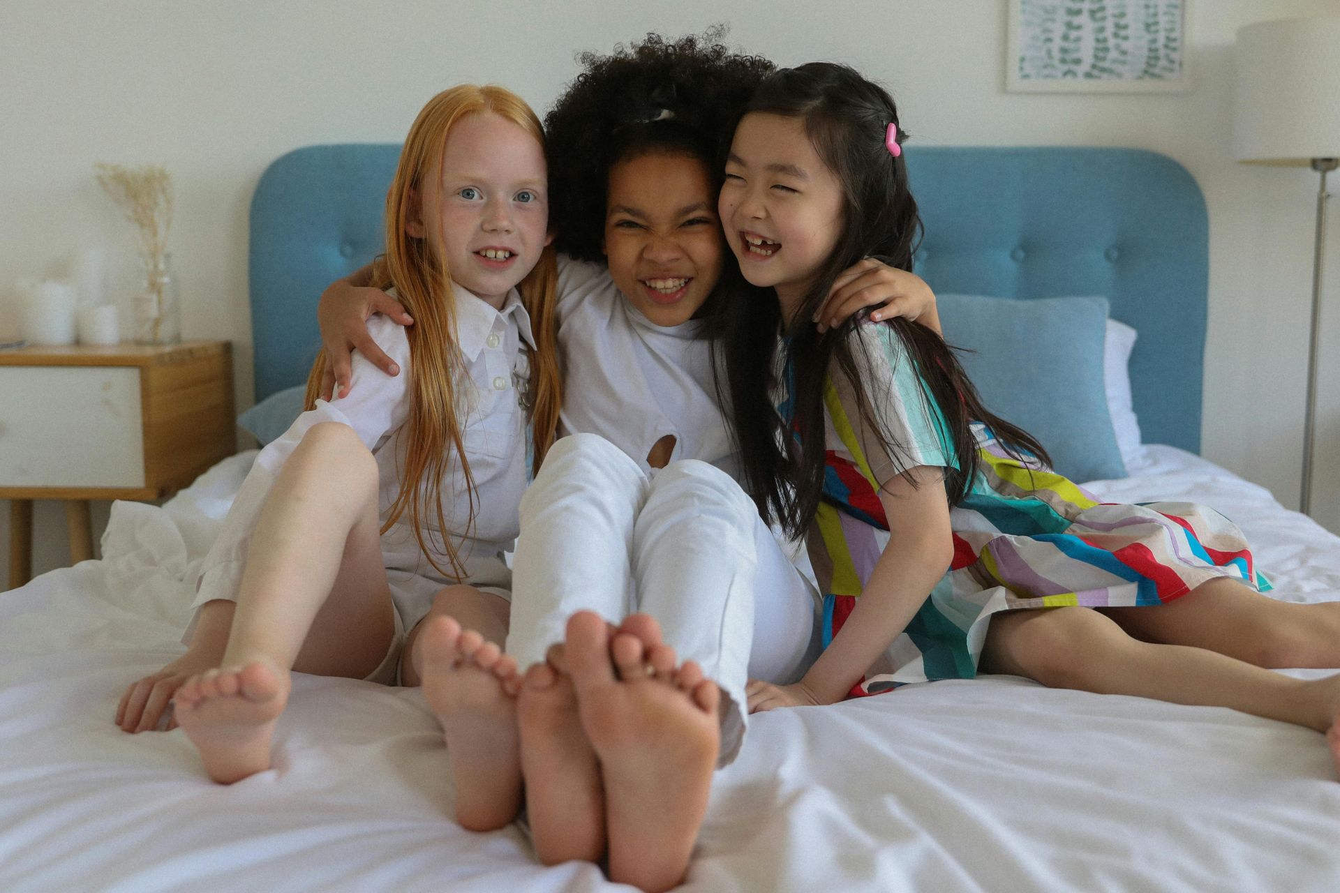 Three happy children hugging on a cozy bed, expressing friendship and joy.