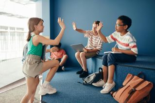 Group of kids high-fiving in a school environment, enjoying a fun educational moment.